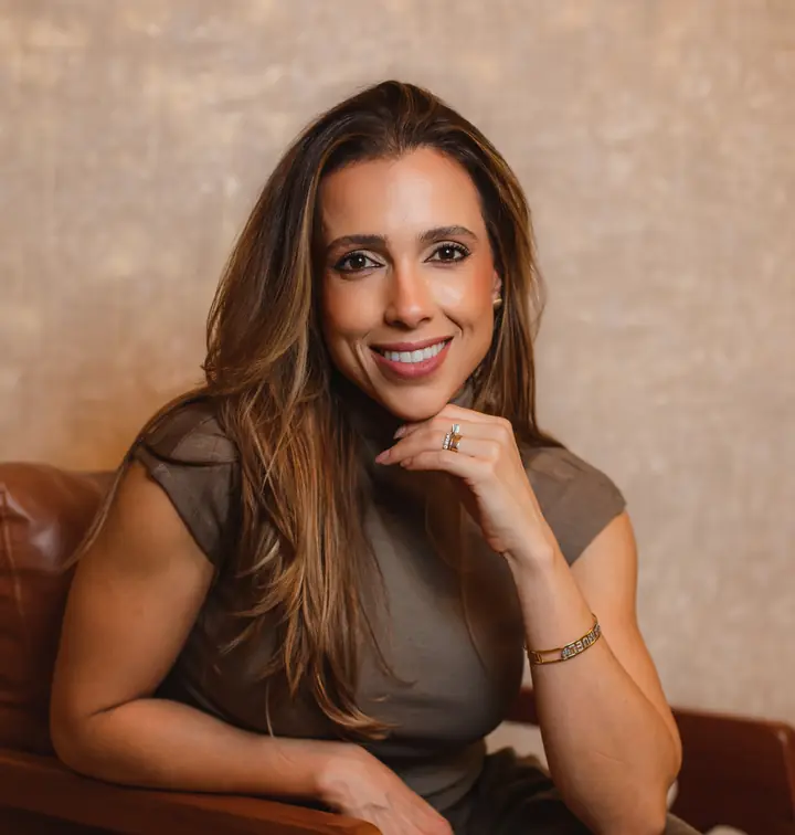 Dra. Raquel Cunha, oftalmologista em Guaxupé, sorrindo em poltrona do Instituto Holos